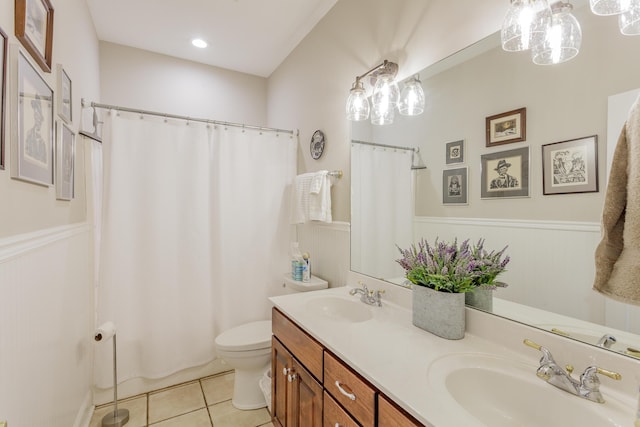 full bath featuring double vanity, toilet, a sink, and tile patterned flooring