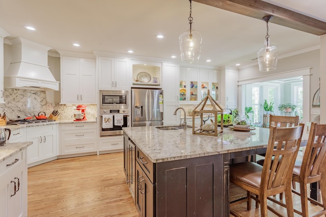 kitchen with backsplash, crown molding, appliances with stainless steel finishes, a sink, and custom range hood