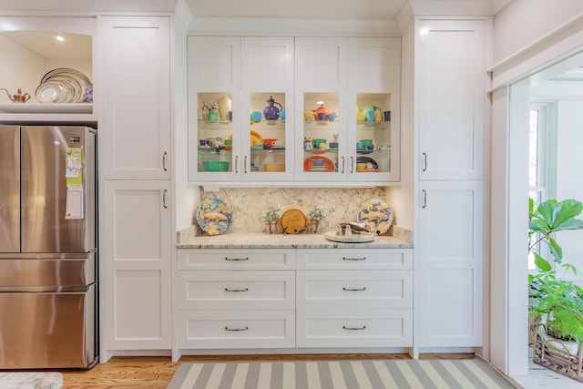 bar with freestanding refrigerator, decorative backsplash, and light wood-style flooring