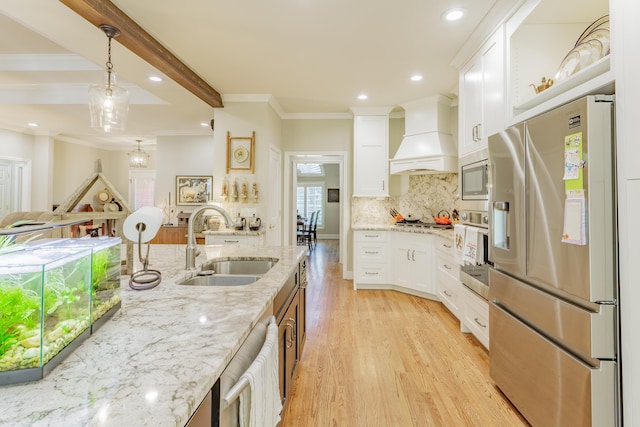 kitchen featuring light wood-type flooring, white cabinets, custom range hood, a sink, and appliances with stainless steel finishes