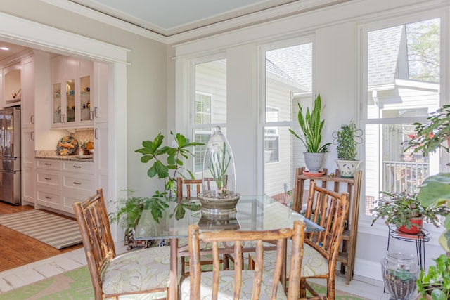 dining space with crown molding and light wood finished floors