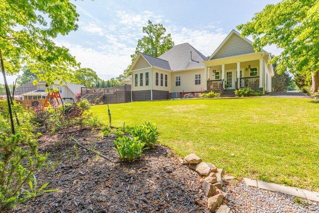 rear view of house featuring a lawn, fence, covered porch, and french doors