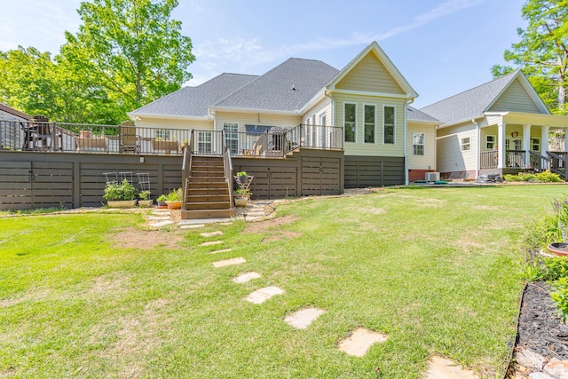 rear view of house with stairway, a lawn, a shingled roof, and a wooden deck
