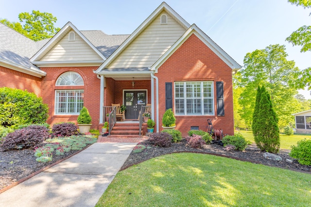 view of front of house featuring french doors, a front yard, and brick siding