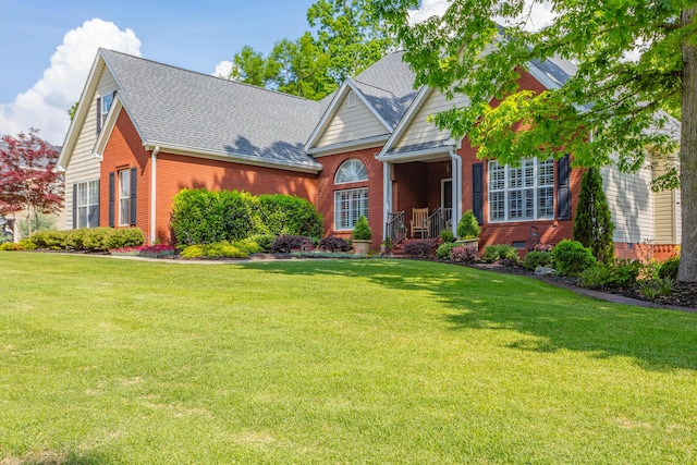 view of front facade with a shingled roof, a front lawn, and brick siding