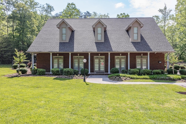cape cod-style house with french doors, a shingled roof, a front lawn, and brick siding