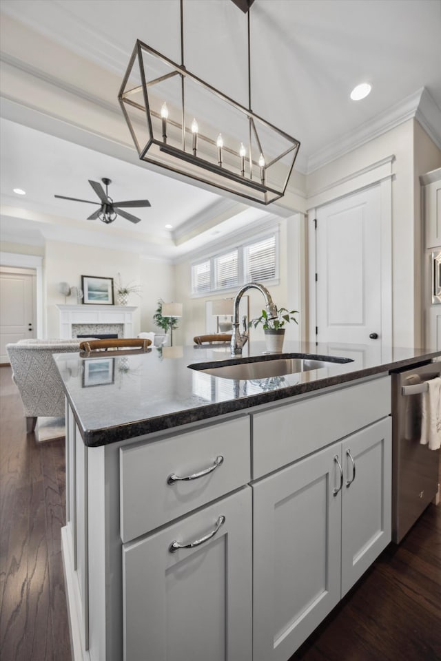 kitchen with a center island with sink, ceiling fan, ornamental molding, a sink, and dishwasher