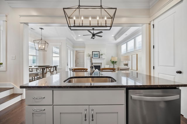 kitchen featuring a fireplace, a kitchen island with sink, ornamental molding, a sink, and dishwasher