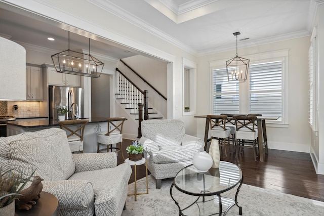 living area featuring ornamental molding, dark wood-style floors, baseboards, a chandelier, and stairs