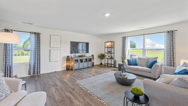 living room featuring visible vents, baseboards, and wood finished floors