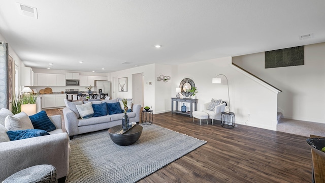 living area with stairway, wood finished floors, visible vents, and baseboards