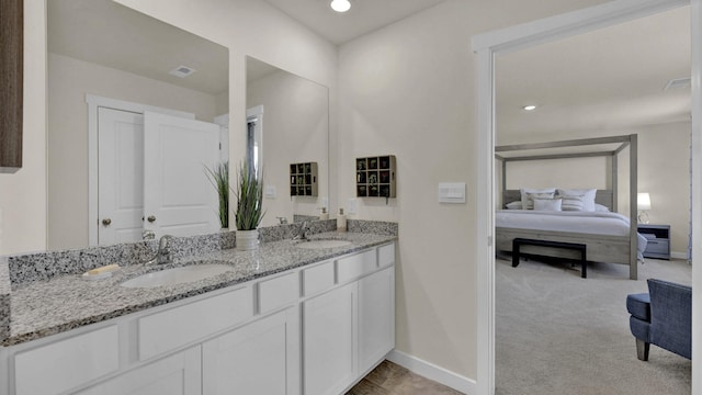 ensuite bathroom featuring a sink, connected bathroom, and baseboards