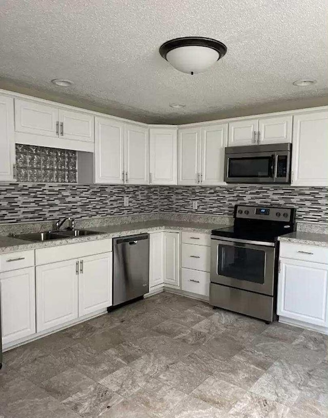 4922 Marylin Ln, Chattanooga, TN 37411 - kitchen featuring stainless steel appliances, a sink, white cabinetry, decorative backsplash, and a textured ceiling