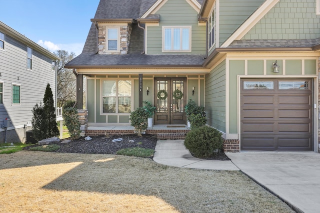 view of front of home featuring a porch, french doors, a shingled roof, and driveway