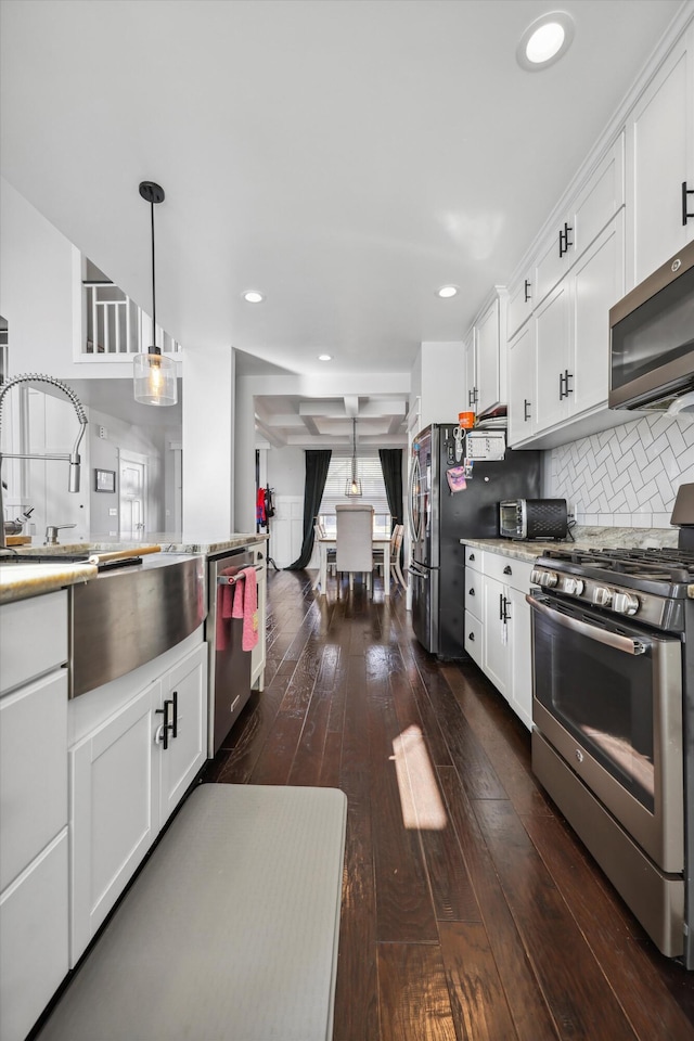 kitchen with decorative light fixtures, appliances with stainless steel finishes, dark wood-style flooring, and white cabinets