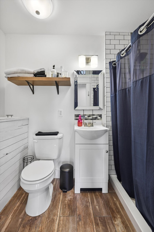 bathroom with curtained shower, toilet, vanity, wood finished floors, and backsplash