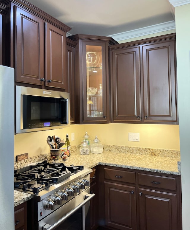 1760 Holden Farm Pl, Ooltewah, TN 37363 - kitchen featuring light stone counters, freestanding refrigerator, dark brown cabinets, glass insert cabinets, and gas range