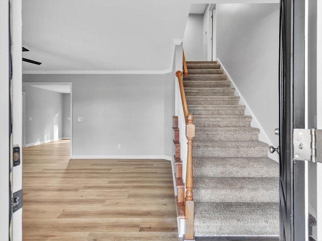 stairs featuring baseboards, wood finished floors, and crown molding