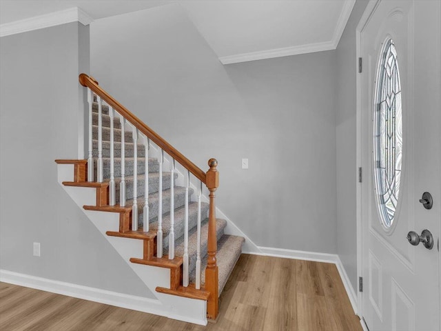 entrance foyer featuring ornamental molding, wood finished floors, and a healthy amount of sunlight