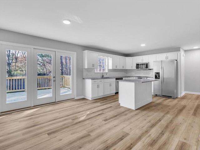 kitchen with light wood-style flooring, a wealth of natural light, stainless steel appliances, and decorative backsplash