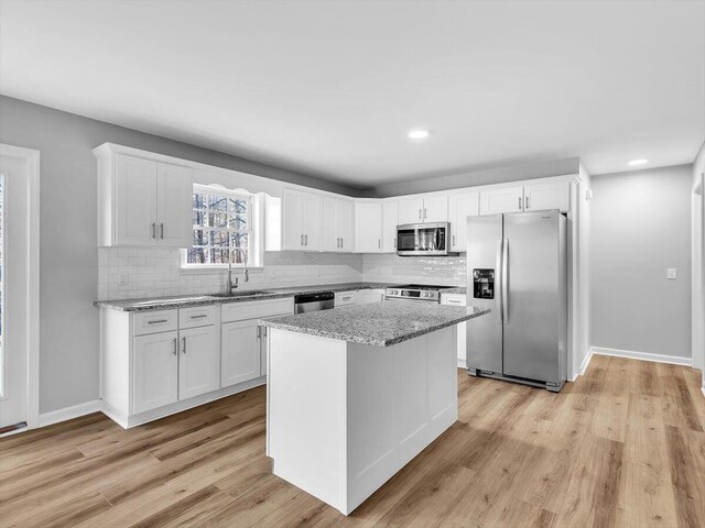 kitchen with decorative backsplash, white cabinetry, a sink, and stainless steel appliances