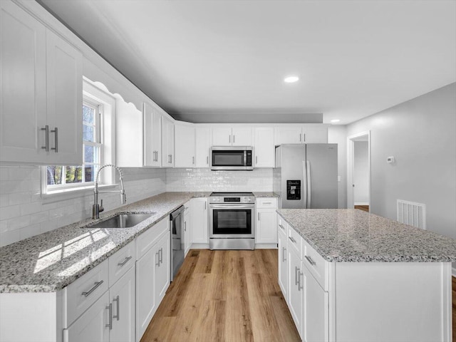 kitchen with visible vents, tasteful backsplash, appliances with stainless steel finishes, a sink, and light wood-type flooring