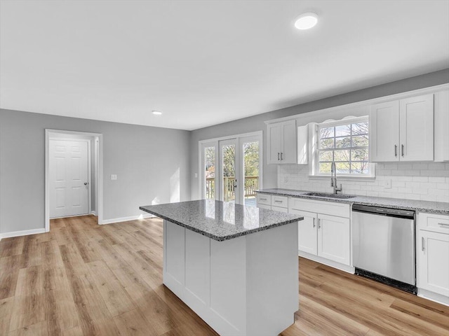kitchen featuring light wood-style flooring, dishwasher, a center island, a sink, and backsplash