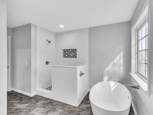 bathroom with a freestanding bath, baseboards, and tiled shower