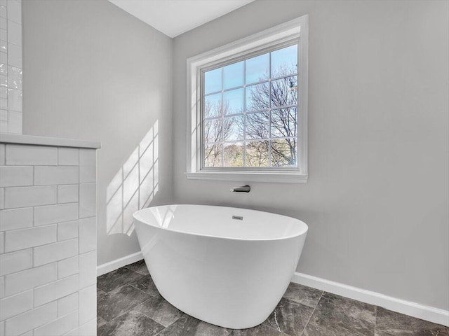 bathroom featuring baseboards and a freestanding tub