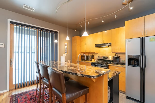 295 W 19th St, Chattanooga, TN 37408 - kitchen with backsplash, a breakfast bar area, under cabinet range hood, stainless steel appliances, and dark stone counters