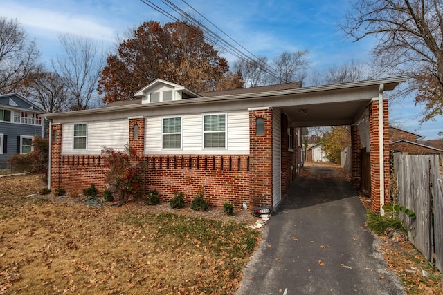 bungalow-style house with a carport, fence, brick siding, and aphalt driveway
