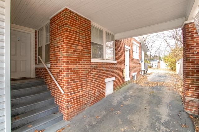 view of side of home with driveway, entry steps, and brick siding
