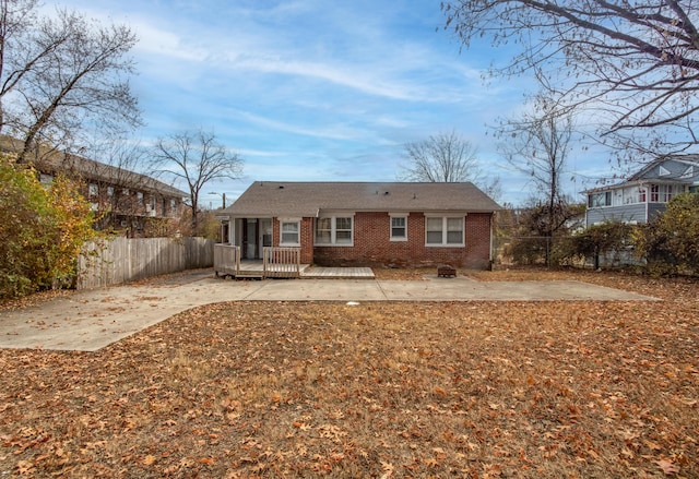 back of property with fence, a wooden deck, a patio, and brick siding