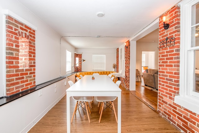 dining area featuring light wood-style flooring and brick wall