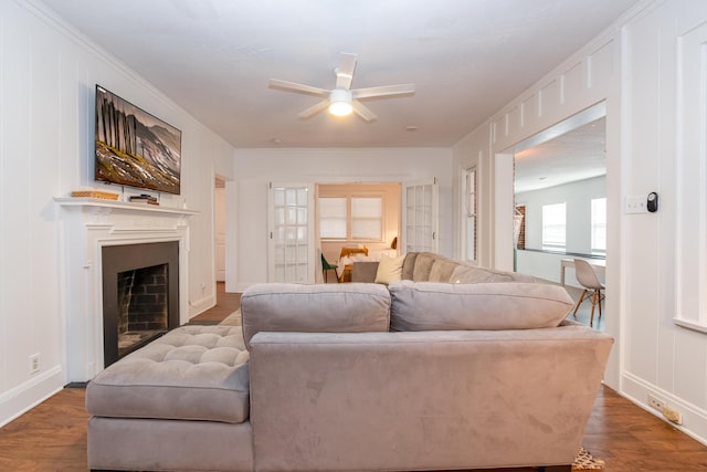 living room with crown molding, baseboards, a fireplace, wood finished floors, and a ceiling fan