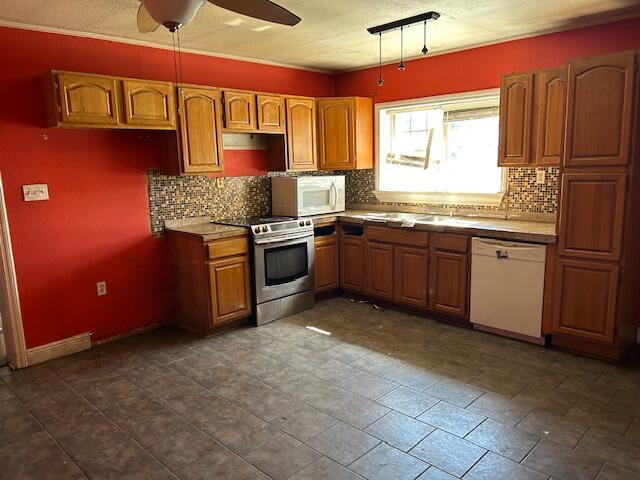 kitchen featuring backsplash, brown cabinets, white appliances, and ceiling fan