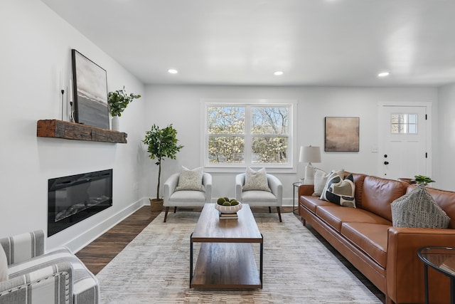 living room featuring recessed lighting, a glass covered fireplace, baseboards, and wood finished floors
