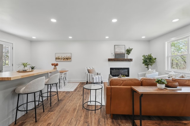 living room featuring baseboards, a glass covered fireplace, recessed lighting, and dark wood finished floors