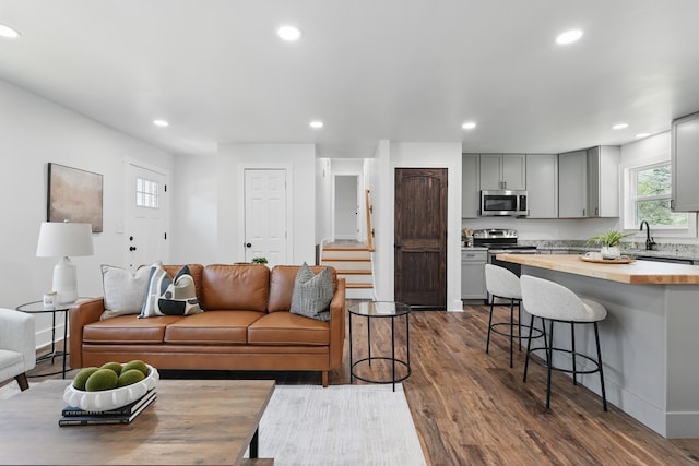 living area with recessed lighting, baseboards, stairway, and dark wood finished floors