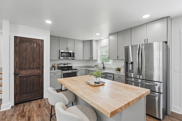 kitchen featuring a sink, wood counters, appliances with stainless steel finishes, and gray cabinetry