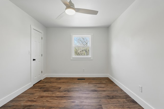 empty room featuring baseboards, visible vents, ceiling fan, and dark wood-style flooring