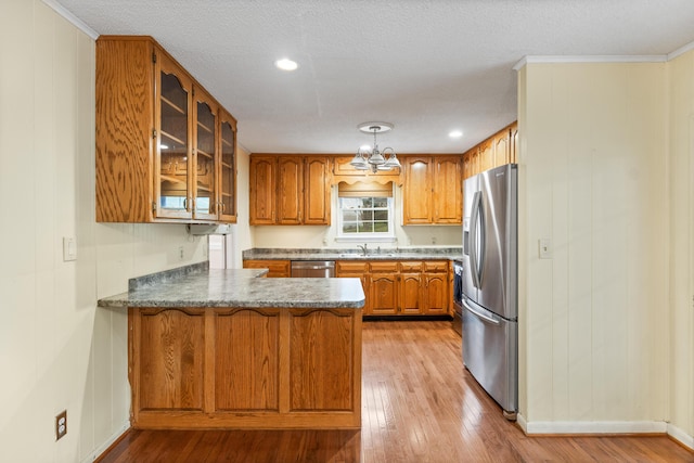 7004 Lystra Rd, Harrison, TN 37341 - kitchen featuring appliances with stainless steel finishes, a peninsula, brown cabinets, glass insert cabinets, and light wood finished floors
