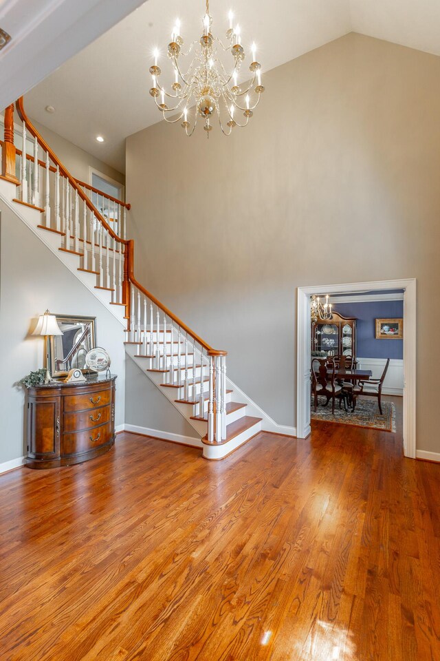 interior space with lofted ceiling, wood finished floors, a chandelier, and baseboards