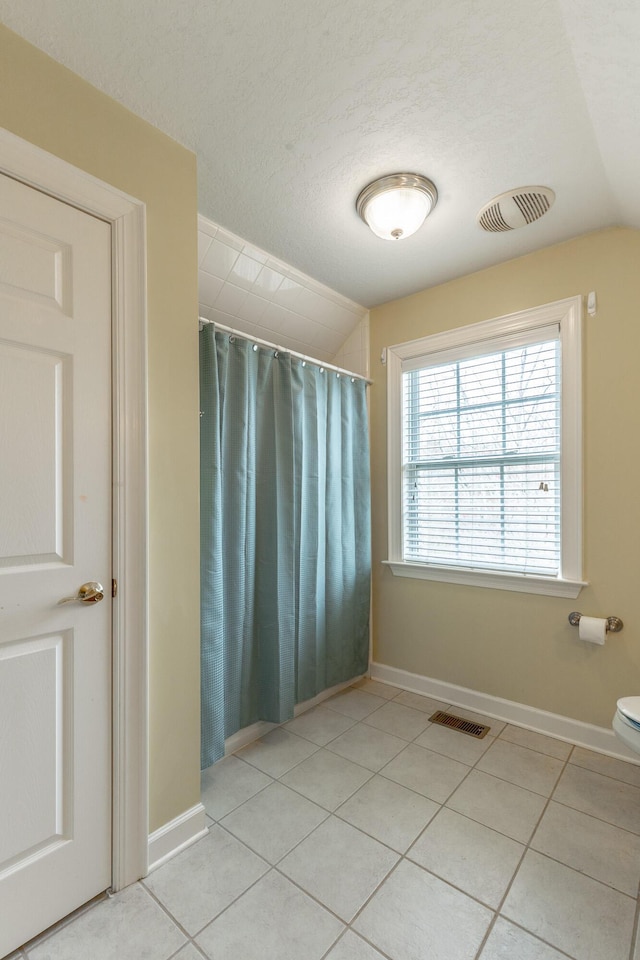 full bath featuring lofted ceiling, visible vents, and tile patterned floors