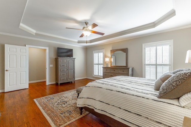 bedroom featuring wood finished floors, a tray ceiling, and crown molding