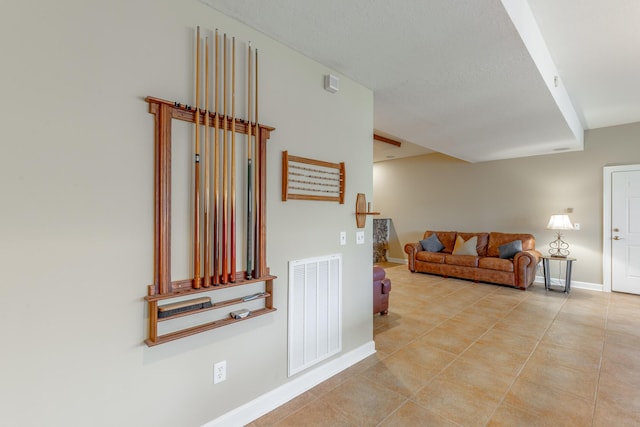 hallway with baseboards, light tile patterned flooring, and visible vents