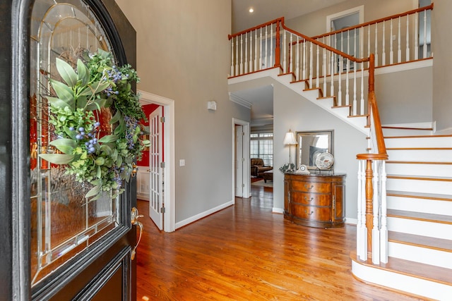 entrance foyer featuring stairway, a high ceiling, baseboards, and wood finished floors