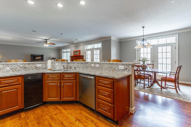 kitchen featuring dishwasher, a sink, brown cabinets, and a healthy amount of sunlight