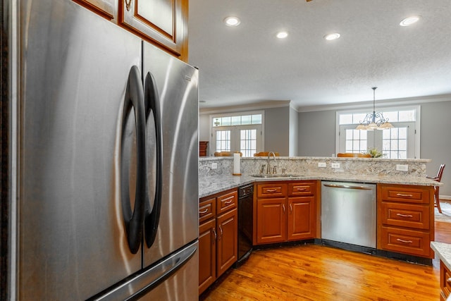 kitchen with crown molding, appliances with stainless steel finishes, a sink, and light wood-type flooring