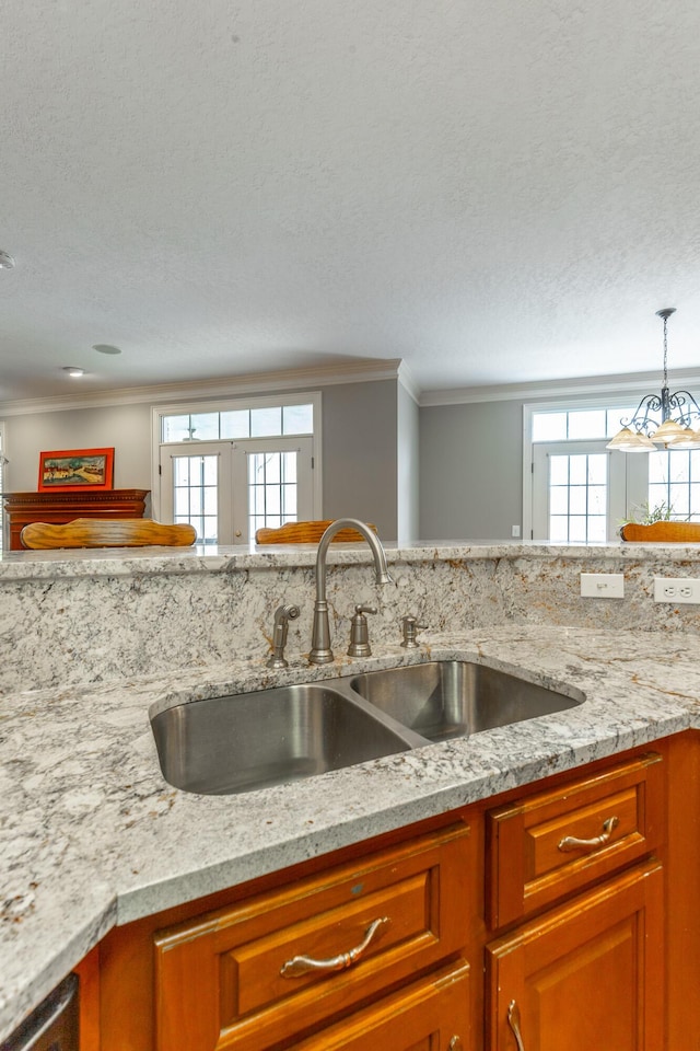 kitchen featuring a wealth of natural light, crown molding, a sink, and a textured ceiling